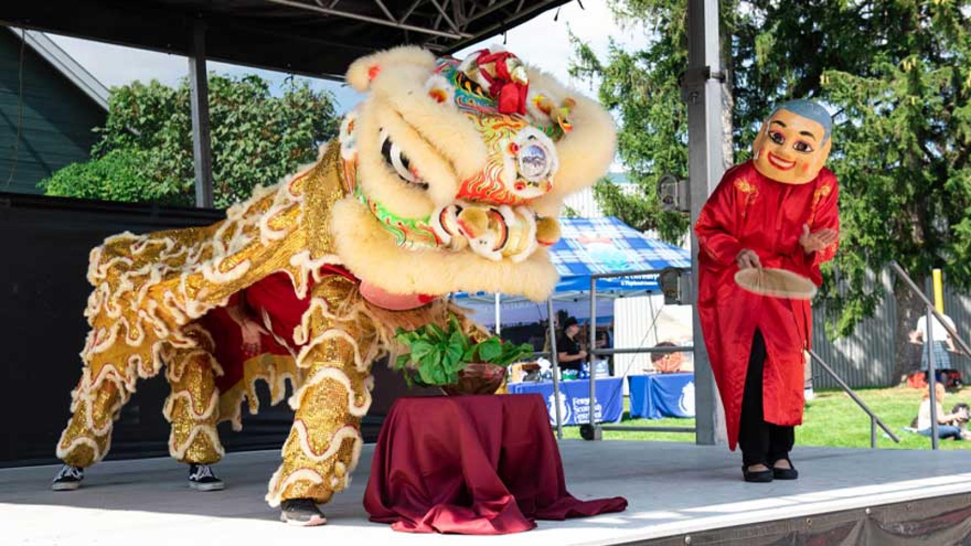Chinese dragon costume with dancers underneath performing on stage at the 2023 multicultural festival