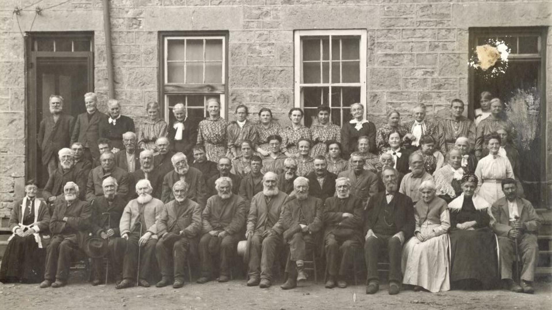 Group portrait of Poor House Inmates in front of the stone wash house, circa 1916