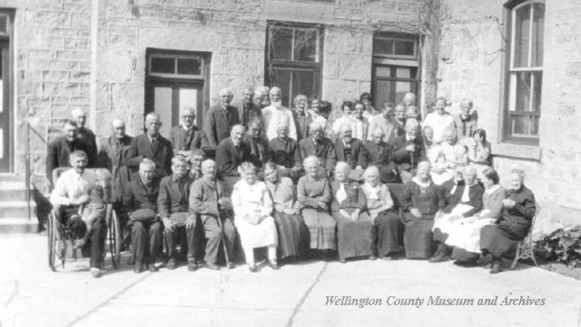 Inmates of Poor House pose for group photo in courtyard