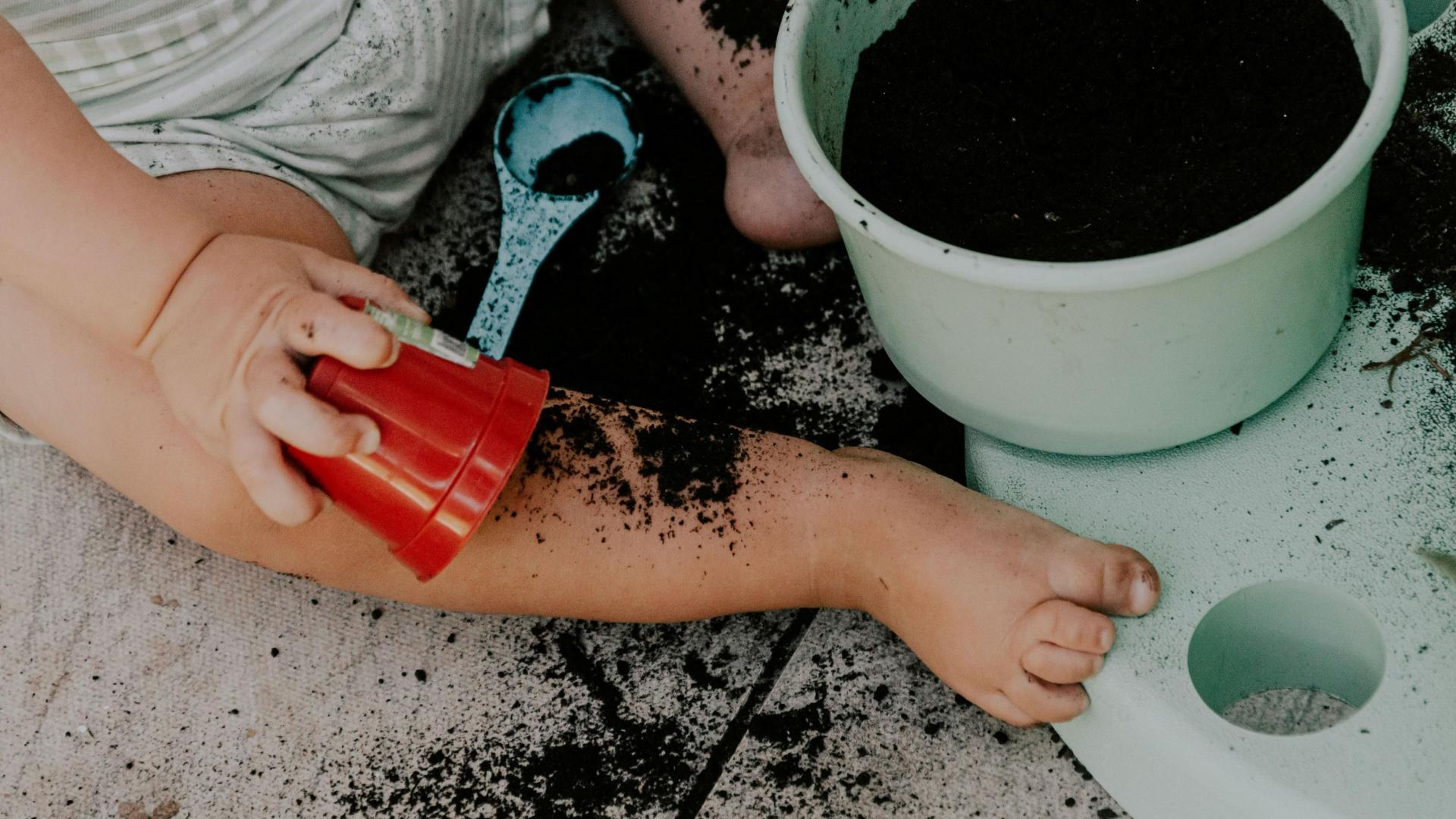 toddler digging in pot of top soil