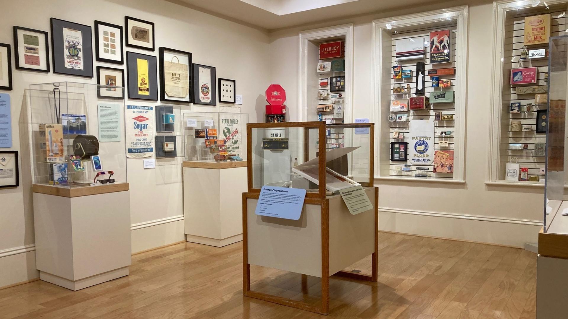 Photo taken from corner of gallery showing multiple display cases and many items displayed on walls.
