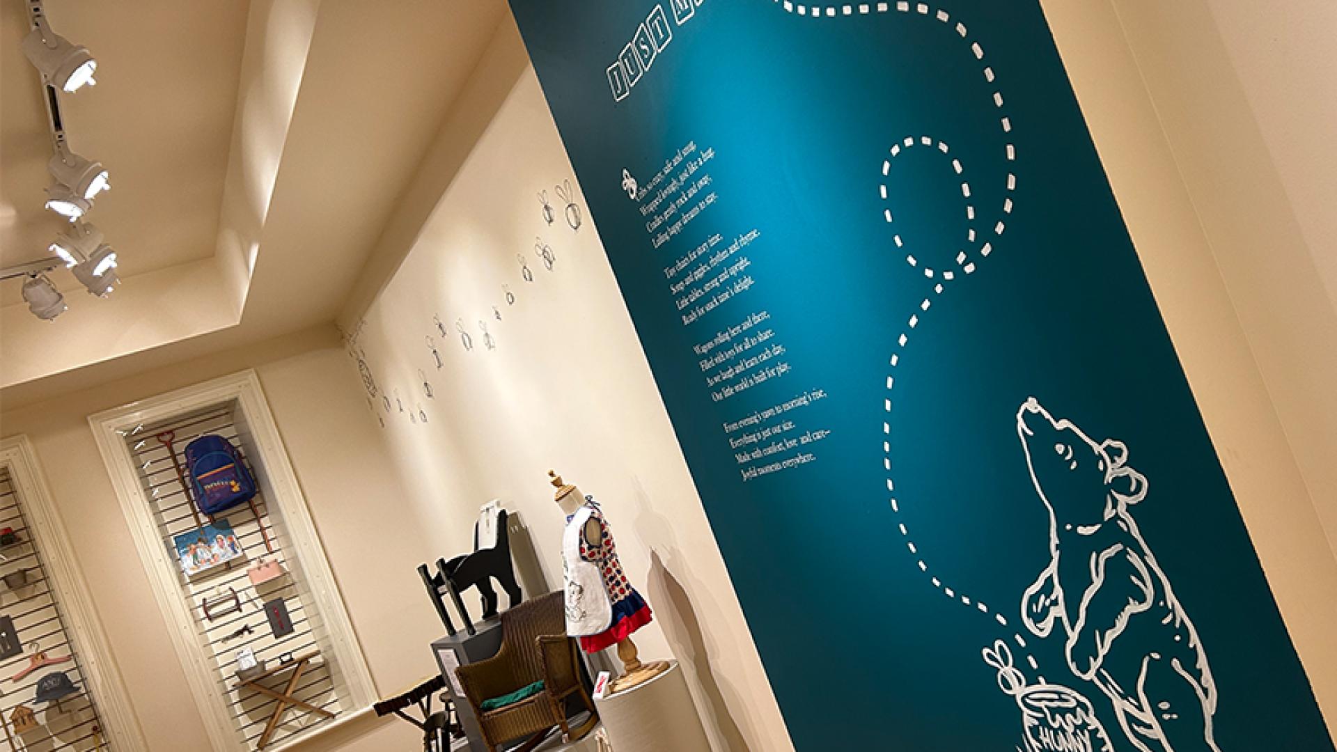 Image of museum exhibit with teal wall and children's furniture and illustrations. 