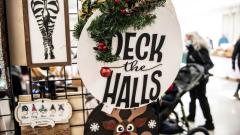 Festive ornaments hang on display for sale at a vendor booth, passing visitors in the background