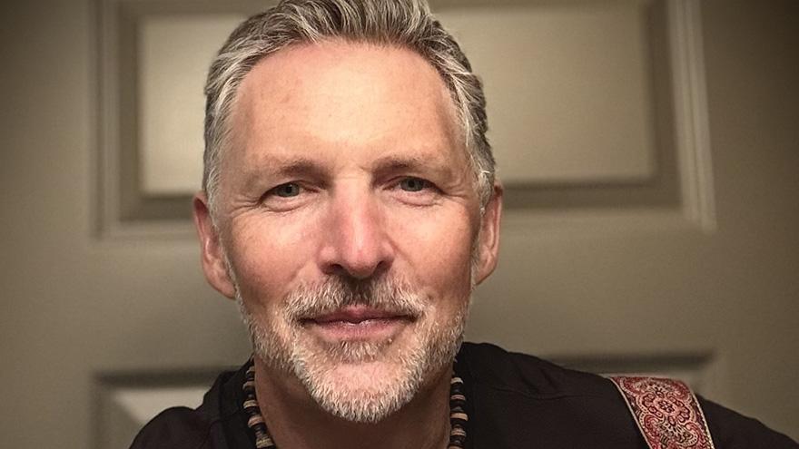 Close up of a middle age musician smiling with greying facial hair