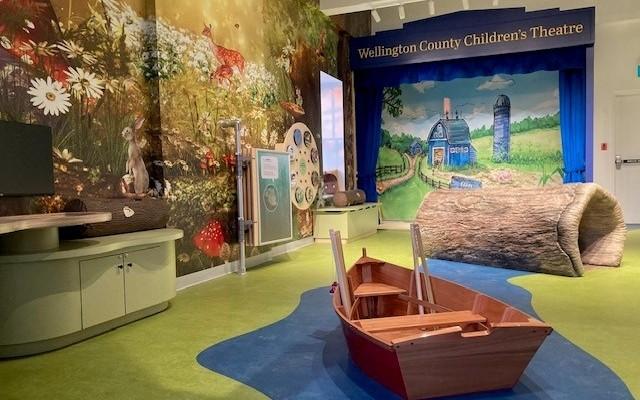 Children's Space with boat, log and stage in background.